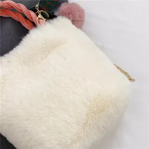 Detailed close-up of fluffy white faux fur texture with pink pompom and gold chain strap