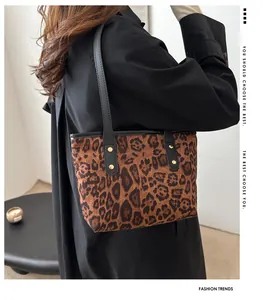 Detail of leopard print tote bag with black leather handles and gold rivet fasteners