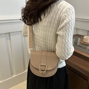 Elegant beige saddle bag with golden buckle and jacquard strap for a modern style