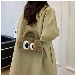 Détail du sac peluche marron avec yeux de dessin animé et chaîne en métal doré