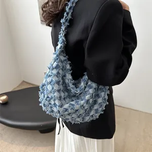 Sac hobo en jean bleu avec motif à carreaux et détails de franges porté par un modèle
