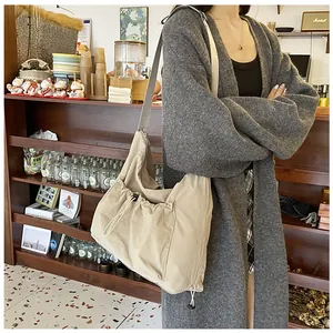 Detail of beige pleated nylon crossbody bag with adjustable strap in casual setting