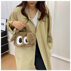 Détail du sac à bandoulière en peluche marron avec chaîne métallique sur un manteau kaki