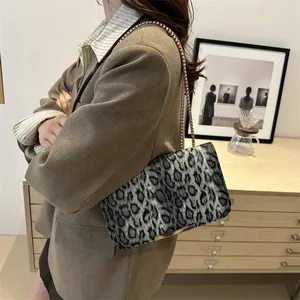 Sac bandoulière léopard tendance avec chaîne dorée porté par un mannequin de profil