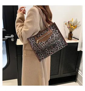 Detail of leopard print tote bag with brown leather handles and golden zipper pocket