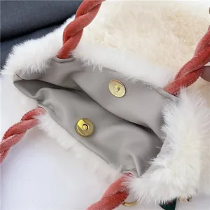 Detail view of plush faux fur handbag featuring gold magnetic buckle and orange twisted handle