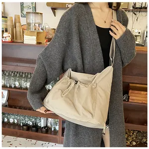 Detailed view of khaki nylon crossbody bag with drawstring front pocket and wide strap