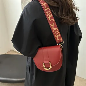 Red leather saddle bag with wide printed strap and golden metal buckle for women