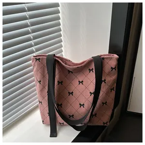 Detail der rosa Cord-Tragetasche mit schwarzen Schleifenmustern und Nylon-Schultergurten