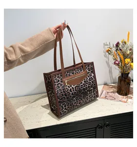 Macro detail of leopard print tote bag with brown leather straps and gold zipper pocket