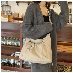 Detail of beige nylon crossbody bag featuring adjustable drawstrings and large front pocket