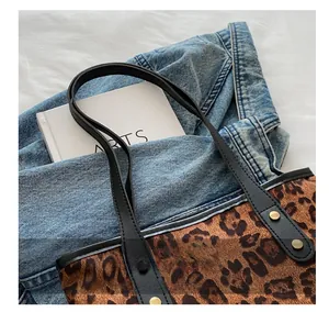 Detail of leopard print tote bag with black leather handle and golden rivet accents