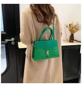 Détail d'un sac à main vert à motif crocodile avec fermoir doré et bandoulière réglable