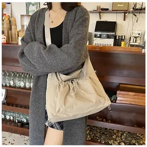 Detail of khaki nylon shoulder bag featuring a functional front drawstring pocket