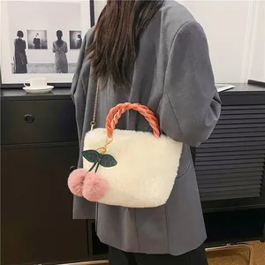 Detail of plush white crossbody bag with orange velvet handle and pink cherry pendant