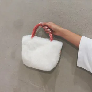 Close-up of white plush handbag with pink braided handle against a gray background