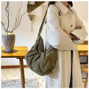 Detail of olive green nylon pleated crossbody bag showing adjustable strap and soft texture