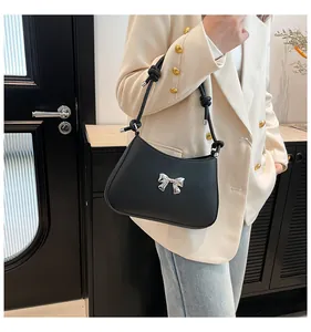 Détail du sac sous le bras en cuir noir avec nœud en métal argenté et bandoulière