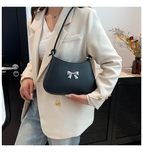 Détail de la boucle en nœud métallique argenté sur un sac porté épaule noir mat
