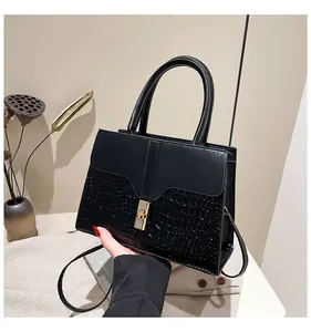 Détail du sac à main noir avec texture crocodile et fermoir rotatif doré élégant