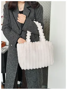 Détail du sac cabas en peluche crème avec rayures verticales et poignée pompon sur manteau