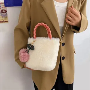Detail of soft white plush handbag with pink braided handle and cherry fur ball charm