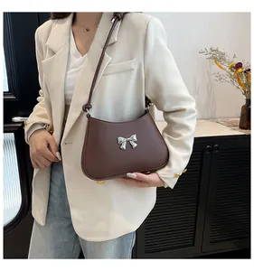 Détail du sac sous l'aisselle en cuir marron foncé avec nœud argenté sur le mannequin