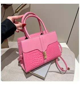 Gros plan du sac à main rose avec texture crocodile et fermoir rotatif en métal doré