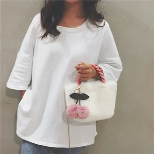 Detail of white faux fur handbag with pink knit handle and cherry pom-pom charm decoration