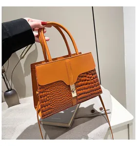 Détail du sac en cuir orange et marron avec boucle métallique dorée rectangulaire