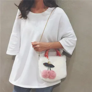 White plush shoulder bag featuring decorative pink cherry pom-poms and gold chain strap