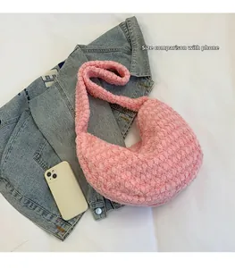 Pink plush crescent shoulder bag shown with a smartphone for phone size comparison