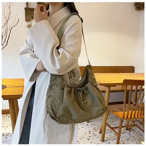 Detail of olive green nylon crescent bag with drawstring texture and wide shoulder strap