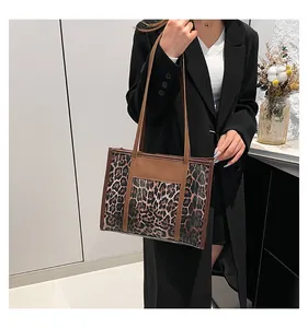 Close-up of leopard print tote bag with brown leather stitching and long handles
