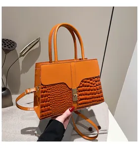 Détail du sac à main orange montrant la texture crocodile et le fermoir en métal doré