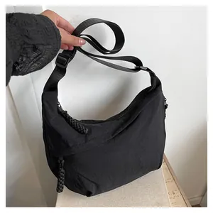 Gros plan du sac hobo en nylon noir avec texture froissée et bandoulière réglable