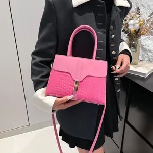 Sac à main rose effet crocodile avec fermoir doré présenté dans un décor d'intérieur chic