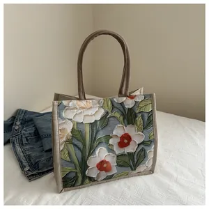 Gros plan détaillé d'un sac cabas en lin avec motif floral en relief sur une literie blanche