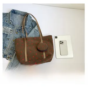 Brown corduroy strawberry tote bag shown next to a tablet and phone for size comparison
