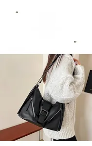 Detailed close-up of a black glossy leather tote bag with silver zippers and buckle