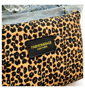 Detail of leopard print fabric texture with leather label and gold zipper on travel bag