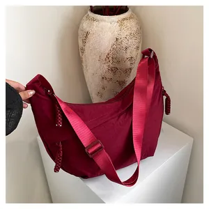 Détail macro du sac croissant en nylon bordeaux montrant la texture et le gland du zip