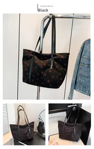 Detail of black corduroy tote bag featuring red strawberry prints and a round charm pouch