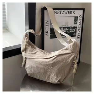 Détail du sac bandoulière en nylon beige avec tirette tressée et large bandoulière en toile