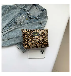 Close-up of leopard print makeup bag with black leather logo patch and zipper detail