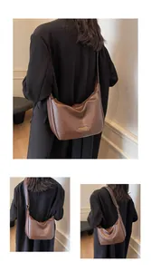 Détail d'un sac hobo marron rétro texturé avec logo doré et bandoulière longue