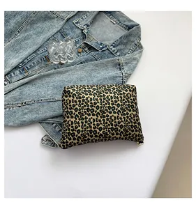 Macro view of leopard print cosmetic bag with gold zipper next to denim jacket