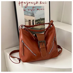 Detail of caramel faux leather tote with decorative zippers and belt buckle on display