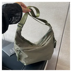 Gros plan sur le sac croissant en nylon vert olive avec bandoulière large et détail zippé