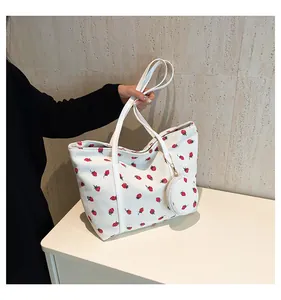 Detail view of white corduroy tote bag with red strawberry prints and small round pouch